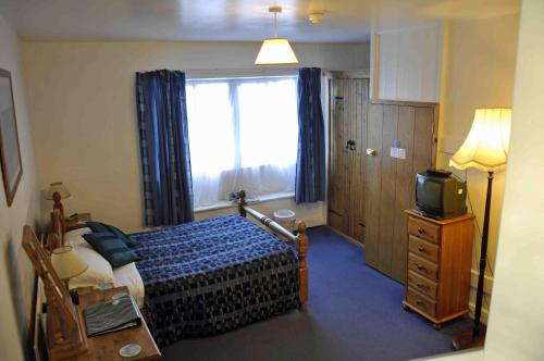 a bedroom with a bed and a window and a television at The White Horse Inn, Clun in Clun
