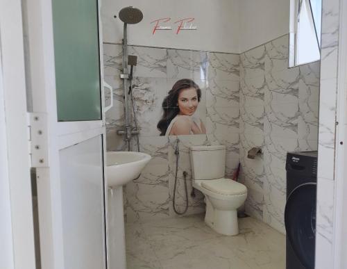 een vrouw in een badkamer met een wastafel en een toilet bij Prince House in Piliyandala