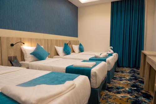 a hotel room with four beds with blue pillows at فندق برادايس لاند الشهداء Paradise Land Hotel Al-Shohada in Al ‘Utaybīyah