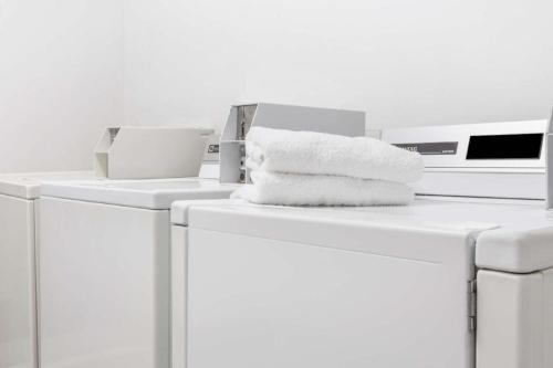 Una pila de toallas encima de las lavadoras. en Ramada Limited Norfolk, en Greenwich