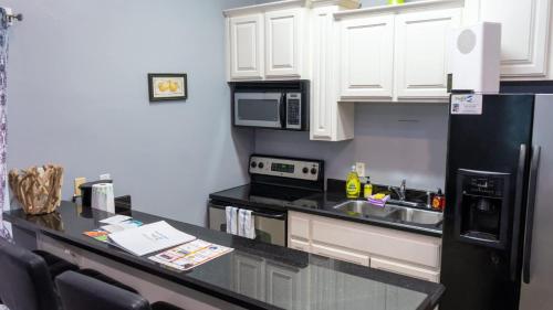 een keuken met witte kasten en een zwarte koelkast bij 100 Steps to Beach Great Value Pool apts in South Padre Island