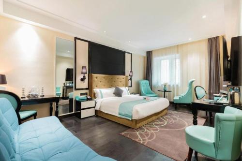 a hotel room with a bed and a desk and chairs at Xana Hotelle· Tianjin Railway Station Jinwan Square Binjiang Avenue in Tianjin