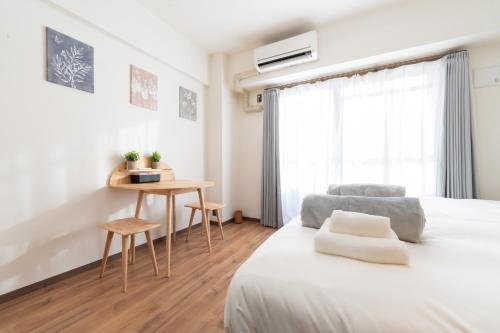 um quarto branco com uma cama e uma mesa em Bloomsbury 402 em Wada