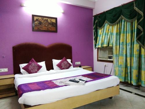 a bedroom with a large bed with purple walls at Hotel Mayur in Gwalior