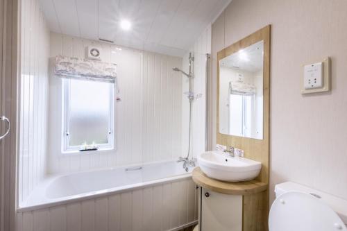 y baño blanco con lavabo, bañera y lavamanos. en Lodge 66 at Riviera Bay Coastal Retreat, en Brixham