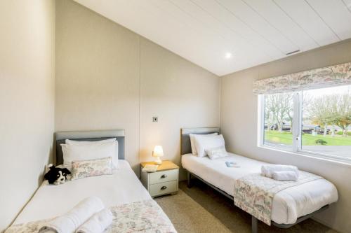 two beds in a room with a window at Lodge 65 at Riviera Bay Coastal Retreat in Brixham