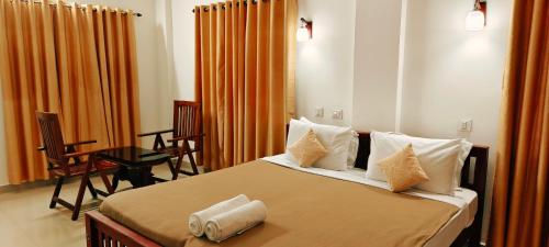 a bedroom with a bed with pillows and a table at Oxxon Airport Hotel in Angamaly