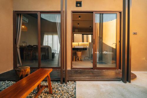 a room with glass doors and a wooden bench at The Fam Cafe&Resort Chiangdao in Chiang Dao