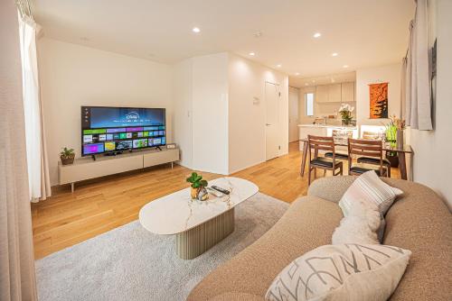 a living room with a couch and a tv and a table at Oasis Omori New House - 30min to Haneda - 2 Adjacent Homes in Tokyo