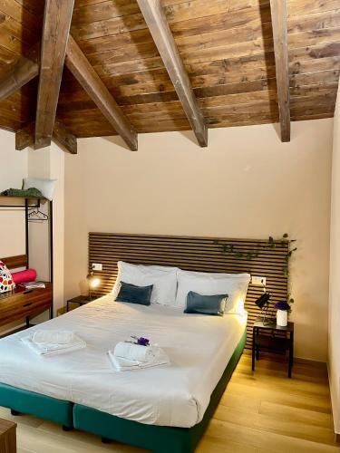 a bedroom with a large white bed with wooden ceilings at Bnbook Residence Matteotti in Novara