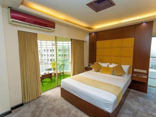 a bedroom with a large bed and a large window at Grand Dhaka Hotel in Dhaka