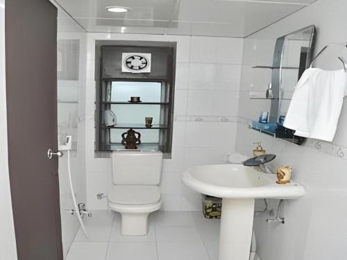 a white bathroom with a toilet and a sink at Grand Dhaka Hotel in Dhaka