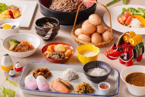 einen Tisch mit Schalen und Teller mit Lebensmitteln in der Unterkunft Aizuwakamatsu Washington Hotel in Aizu-Wakamatsu