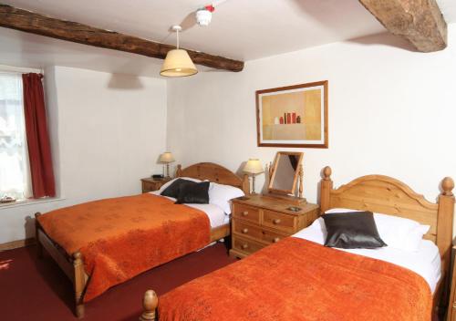 a bedroom with two beds and a dresser at The White Horse Inn, Clun in Clun