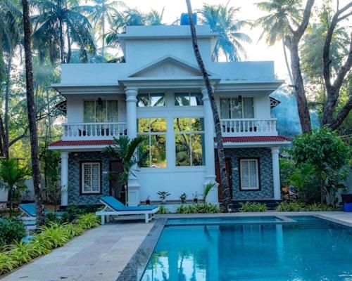 una casa con piscina delante de una casa en Nature's Inn Luxury Villa Morjim Goa, 4bhk and Sparkling Pool, en Morjim