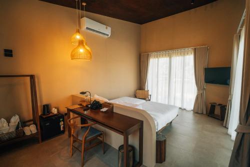 a bedroom with a bed and a desk and a window at The Fam Cafe&Resort Chiangdao in Chiang Dao