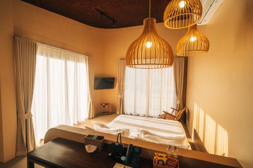 The Fam Cafe&Resort Chiangdao في تشينغ داو: غرفة نوم بها سرير ومصباح معلق