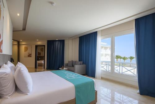 a bedroom with a large bed with blue curtains at Flow Spectrum Resort Sahl Hasheesh in Hurghada