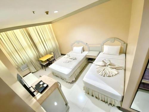 um quarto de hotel com duas camas e uma escrivaninha em Cebu Northwinds Hotel em Cebu