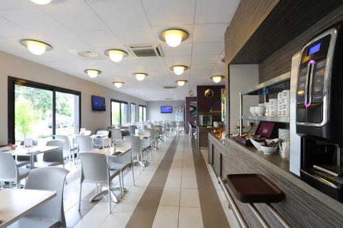 un restaurant avec des tables blanches et des chaises blanches dans l'établissement EastLodge Lyon Est Eurexpo, à Saint-Priest