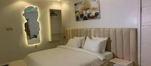 um quarto com uma cama branca e 2 espelhos em Mcangello apartments em Idimu