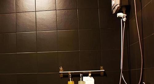 Un baño con ducha con pared de azulejos. en Iroom Hotel, en Suratthani