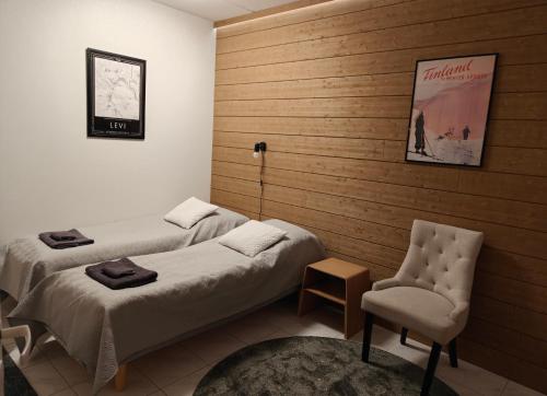 una stanza d'albergo con due letti e una sedia di Levi Jaihki Apartments a Levi