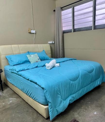 a bed with a blue comforter and blue pillows at Little Stay Inn in Taiping