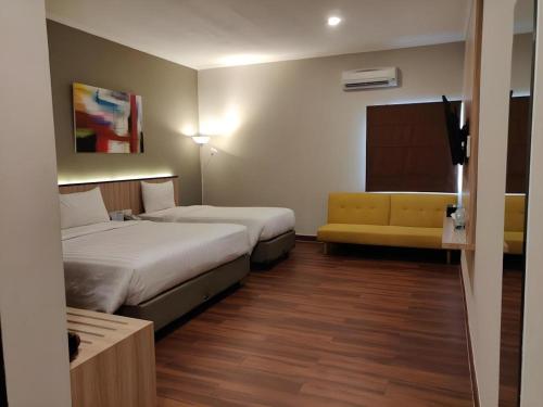 una habitación de hotel con dos camas y un sofá en Havana Mutiara Belitung, en Tanjung Pandan