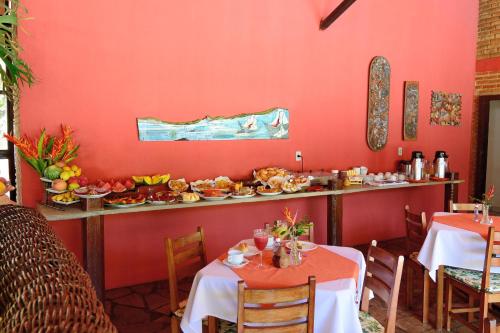 een restaurant met rode muren en tafels met eten op een toonbank bij Pousada Casa de Maria in Prado