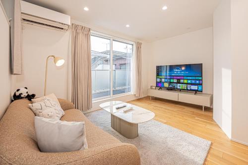 a living room with a couch and a tv at Oasis Omori New House - 30min to Haneda - 2 Adjacent Homes in Tokyo