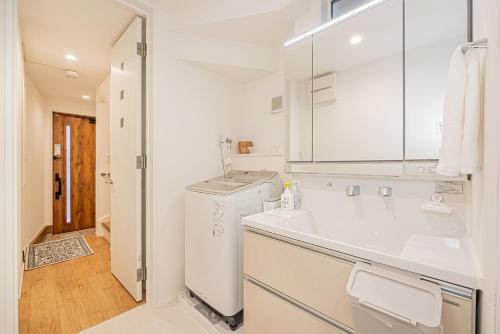 a white bathroom with a sink and a washer and dryer at Oasis Omori New House - 30min to Haneda - 2 Adjacent Homes in Tokyo