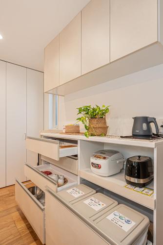 a kitchen with white cabinets and a refrigerator at Oasis Omori New House - 30min to Haneda - 2 Adjacent Homes in Tokyo