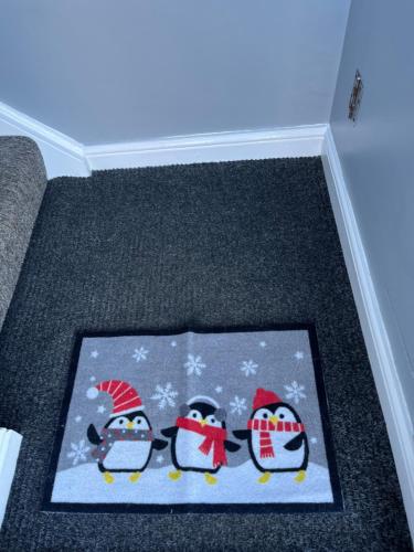 un tappeto natalizio con tre pinguini sul pavimento di Apartment 288 a Lower Swanwick