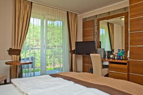 a hotel room with a bed and a desk and a window at Hotel 77 Restauracja Spa in Chałupy