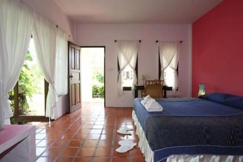 a bedroom with a blue bed and a red wall at Baan Chuengkao Resort in Ranong