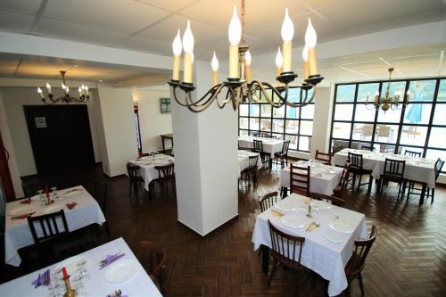 a restaurant with white tables and chairs and a chandelier at Mai Danube in Eşelniţa