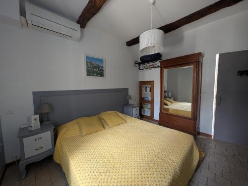 L'angélus, gîte de charme au coeur du vieux village de Sablet في Sablet: غرفة نوم بها سرير ومرآة كبيرة