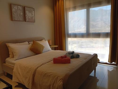 ein Bett mit zwei Stofftieren darauf und einem Fenster in der Unterkunft SifahSeaSun in As Sīfah