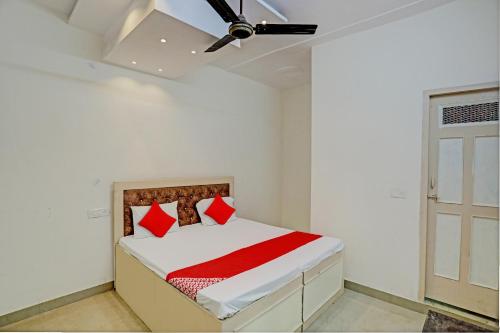 een slaapkamer met een bed met rode kussens en een plafondventilator bij Hotel O Krishna Inn in Ghaziabad