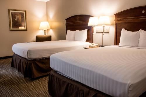 two beds in a hotel room with two lamps at Greenstay Hotel & Suites Central in Springfield