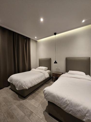 two beds in a room with white sheets at RV Villas Deadsea in Sowayma