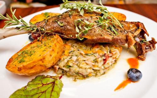 a white plate of food with meat and rice at Hotel 77 Restauracja Spa in Chałupy