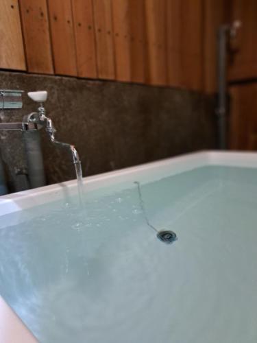 a bath tub with water coming out of it at Atami Onsen Apart 103専用温泉付き客室 in Atami