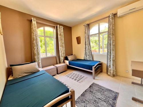 a bedroom with two beds and two windows at Bazaar Square Lodges in Grand-Baie