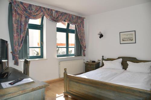 a bedroom with a bed and two windows at Altstadthotel Garni Schlundhaus & Rautenkranz in Meiningen