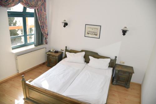 a bedroom with a bed with white sheets and pillows at Altstadthotel Garni Schlundhaus & Rautenkranz in Meiningen