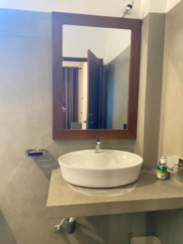 een witte wastafel in een badkamer met een spiegel bij Mango House in Dikwella