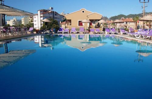 a large pool of blue water with purple lounge chairs at Reis Maris Hotel in Marmaris