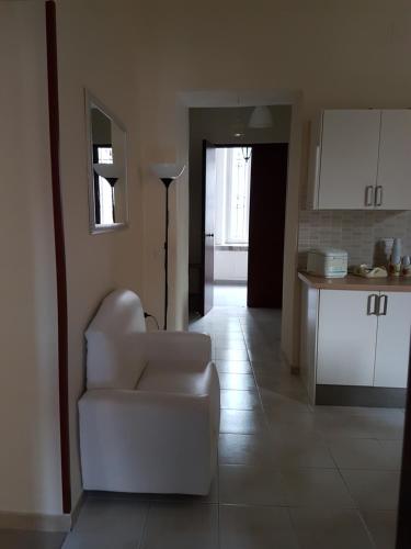 een woonkamer met een witte stoel en een keuken bij La Piccola Reggia in Napels
